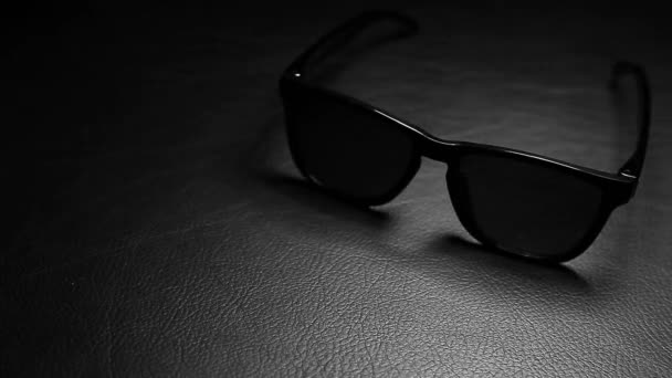 Filmmaterial Von Sonnenbrille Dunklem Lederhintergrund — Stockvideo