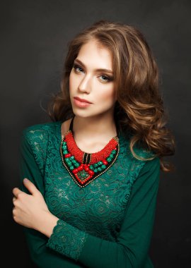 Güzel kadın Model mükemmel dalgalı saç ve makyaj. Kadın yeşil elbise ve kırmızı mercan kolye Blackboard arka plan üzerinde