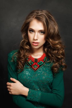 Sevimli kadın moda Model yeşil renkli bir elbise ve kırmızı mercan kolye siyah arka plan üzerinde. Kız mükemmel dalgalı saç modeli ile
