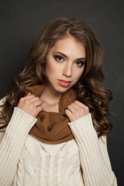 Kıvırcık saç sevimli genç kadınla. Koyu arka plan üzerinde beyaz kazak moda modeli