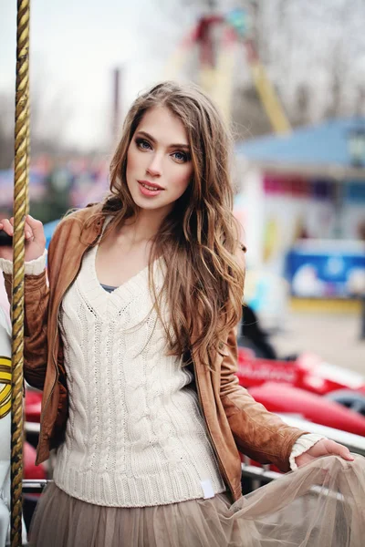 Uzun kahverengi saçları ve makyaj atlıkarınca açık havada güzel genç kadın. Güzel kız portre