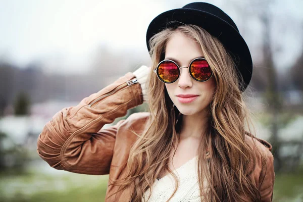 Young happy woman with long brown hair in sunglasses and black hat, portrait