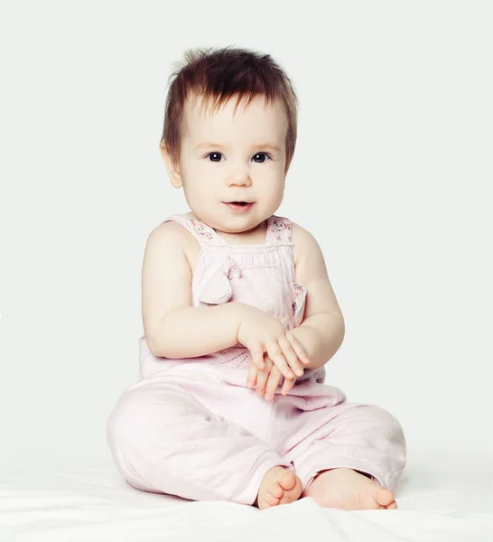 Красива Маленька Дівчинка Рожевому Комбінезоні Сидить Білому Тлі — стокове фото
