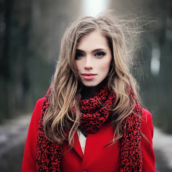Young woman with long blowing hair outdoors. Lady in red