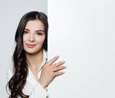 Genç güzel esmer kadın beyaz boş kağıt afiş arka plan ile. Mutlu gülümseyen kadın. Reklam Pazarlama, iş ve eğitim kavramı. 