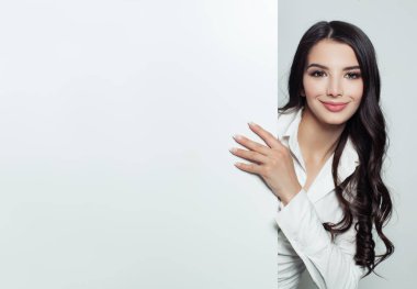Mutlu işkadını beyaz boş afiş arka plan kopya alanı için advertisiment veya kısa mesaj ile gösterilen. İş ve eğitim kavramı. Gülümseyen ve tabela holding uzun kahverengi saçlı genç öğrenci kadın