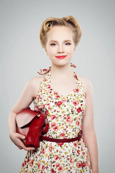 Beautiful blonde woman with retro hairstyle, fashionable makeup, handbag and dress pinup