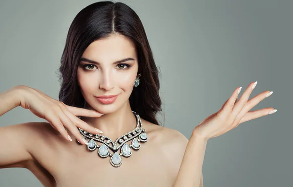 Glamorous Woman in Jewelry Necklace Showing Blank Empty Copy Space on the Open Hand on Gray Background. Product Placement and Advertising Marketing Concept