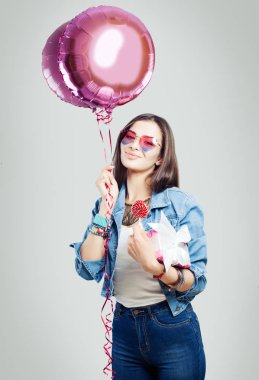 Mutlu genç kadın eğlenmeye hediye, şeker ve pembe balonlu. Doğum günü tatil arka plan