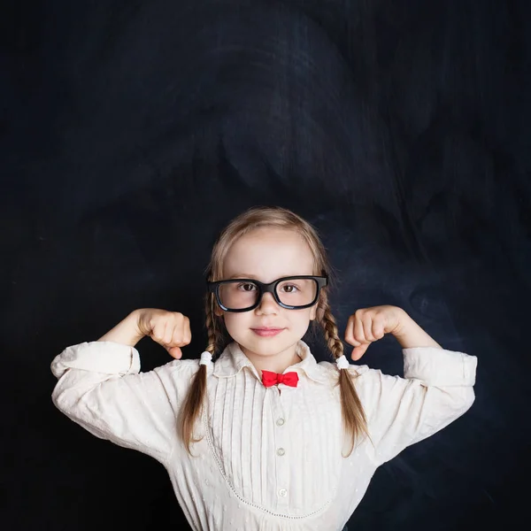 Cute Child on Empty Chalkboard Background. School Girl Power, Creativity and Education Concept