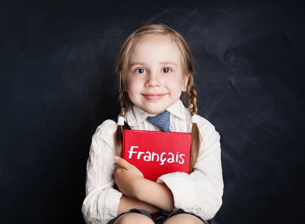 stock image Smiling child girl student with education book on blackboard background, learning french concept