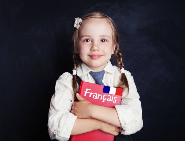 Mutlu çocuk kız öğrenci ile Fransızca Dil Okulu kara tahta karşı kitap çalışma. Fransız kavram öğrenme