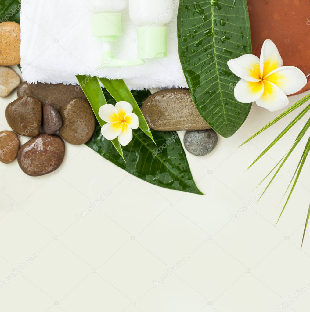 tropical flowers, bowl of water, towel, stones and two green cream tube. Body care and spa concept