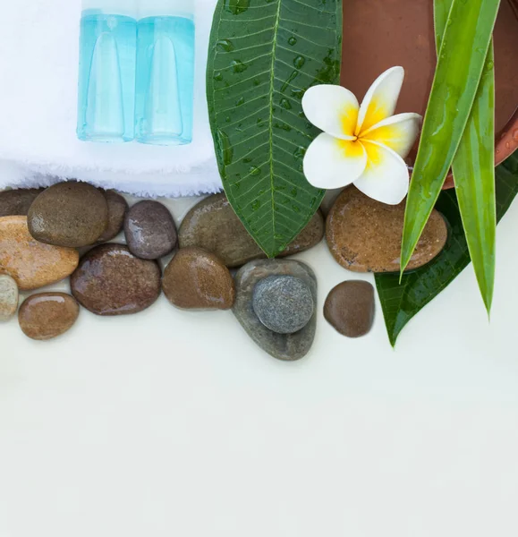 Spa or wellness background with white towels, tropical leaves, flowers, body and face care tools and accessories on white background, top view
