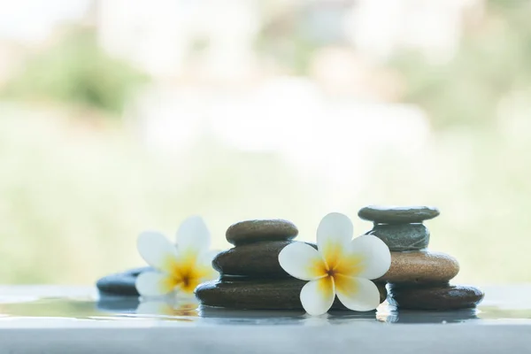 Two sets of spa objects for massage treatment on white table outdoors