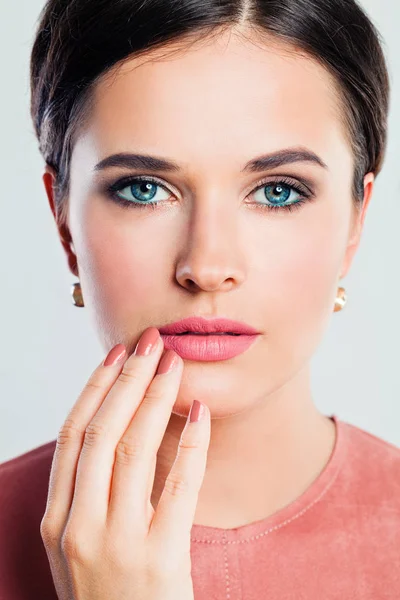 Female face closeup. Gorgeous woman with makeup and manicured hand. Pink lips and nails