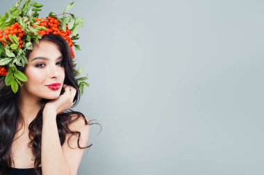 Mutlu genç kadın esmer uzun sağlıklı dalgalı saç, makyaj ve kırmızı çilek ve yeşil ile saç modeli içinde bırakır