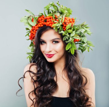 Mutlu esmer kadın moda modeli ile sağlıklı kıvırcık saç modeli, makyaj ve kırmızı çilek ve yeşil yaprakları, portre