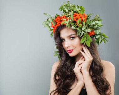 Çekici kadın moda modeli ile sağlıklı kıvırcık saç, makyaj ve kırmızı çilek ve yeşil yaprakları çelenk