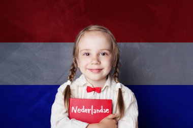 Gülümseyen ve Felemenk dil okulda kitap tutan kız güzel çocuk. Öğrenme Hollandaca