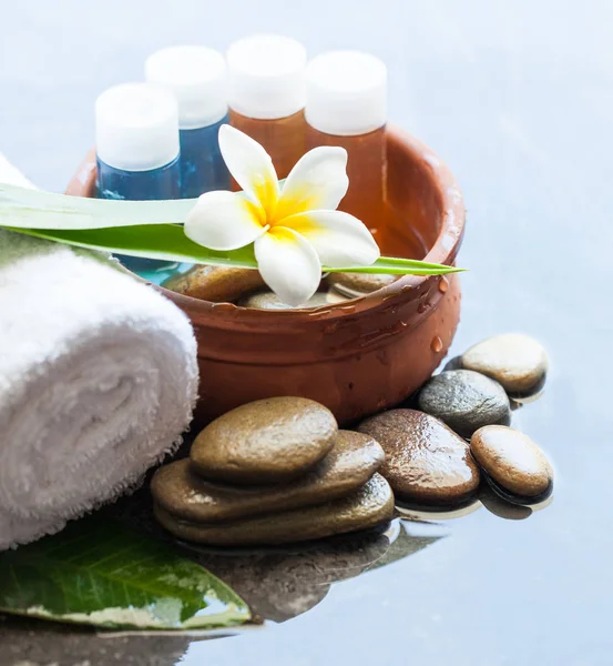 Spa or wellness small bottles with oil for massage treatment and bowl of water, towel.