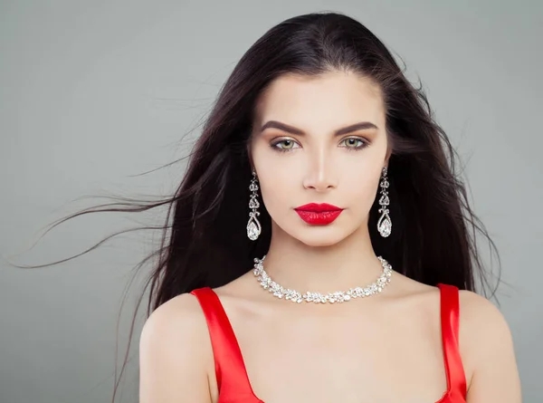 Glamorous woman with blowing hair, red lips makeup and diamond necklace. Fashion portrait