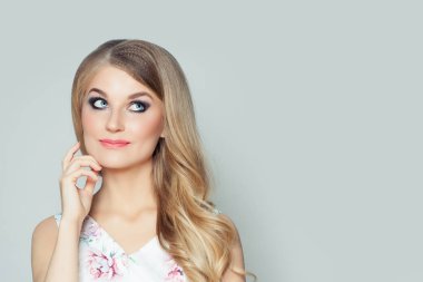 Düşünme ve beyaz duvar arka plan kopya alanı ile bakarken mutlu kadın