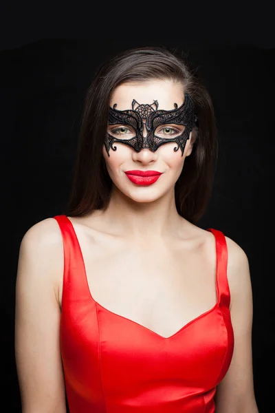Nice woman fashion model in black mask smiling on dark background