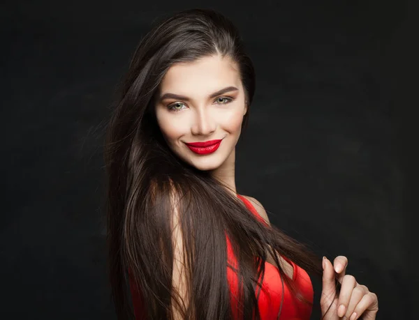 Happy brunette woman with long straight hair on black background, portrait