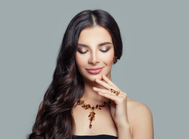 Gülümseyen uzun dalgalı saç, makyaj ve altın kolye, moda portre ile esmer kadın