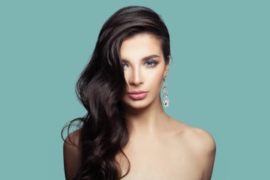 Makyaj ve gümüş küpe elmas mavi zemin üzerine olan güzel kadın