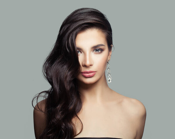 Привлекательная молодая женщина с макияжем, длинными темными волосами и бриллиантовыми серьгами
