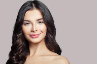 Genç gülümseyen kız. Güzel kadın model yüz. Makyaj, kıvırcık saçları, pembe bir arka plan üzerinde sevimli gülümseme