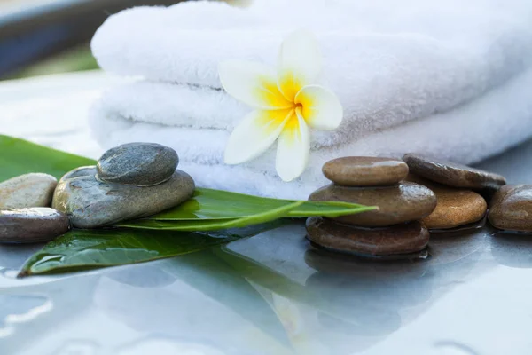 White towel with tropical flower and stones for massage