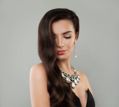 Gülümseyen kadın esmer makyaj, uzun kahverengi saçlı ve elmas kolye ve küpe, moda portre 