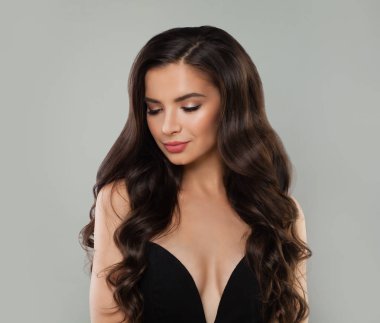 Esmer güzellik. Gri arka plan üzerinde uzun dalgalı saçlı güzel kadın