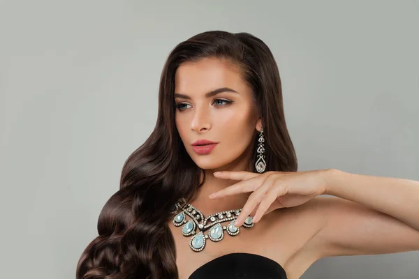 Beautiful young woman fashion model with jewelry, makeup and curly hairstyle