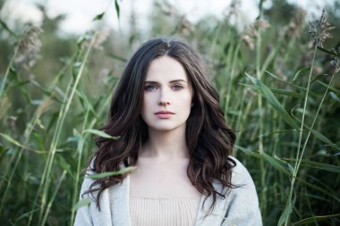 Romantik kız bulutlu bahar gökyüzü karşı yürüyüş. Yeşil yaprakları arka plan üzerinde güzel kadın