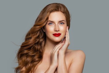 Zencefil üzerinde mavi arka plan kıvırcık olan güzel kadın. Ona dokunmayı kıvırcık saç modeli ile şık Kızıl saçlı kız yüz elini