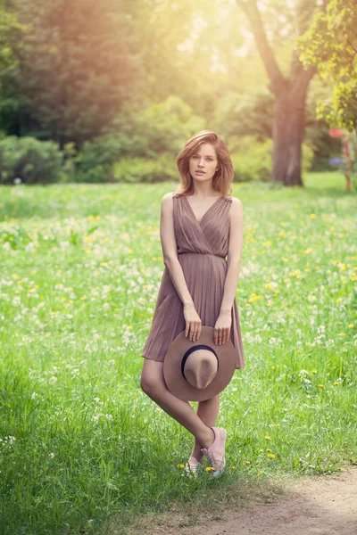 Mulher alegre com chapéu andando no parque ao ar livre na grama verde — Fotografia de Stock