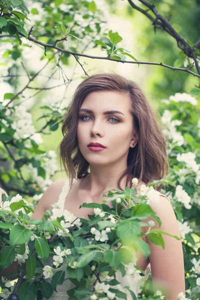 Beautiful young spring woman in white flowers in blooming garden — Stock Photo, Image