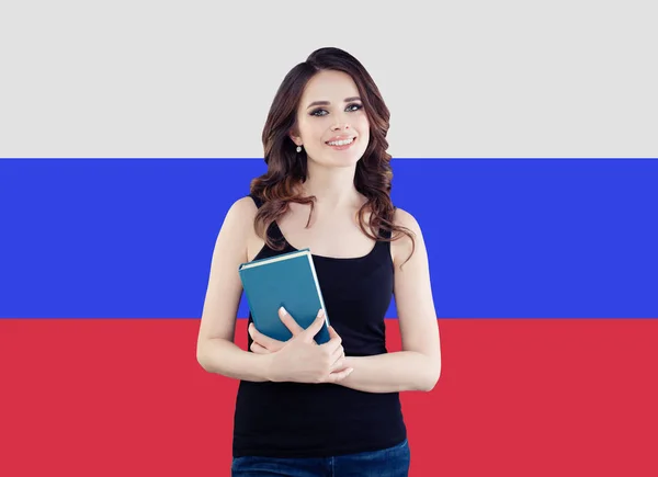 Retrato de menina bonita feliz com livro contra o fundo da bandeira da Federação Russa. Viajar e aprender russo conceito de idioma — Fotografia de Stock