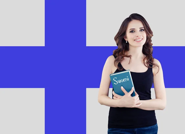 Retrato de una joven feliz y alegre mujer con libro sobre la bandera finlandesa — Foto de Stock