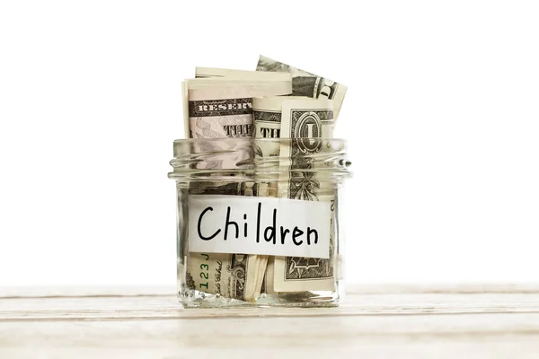 Vaso di vetro con i soldi per i bambini sul tavolo di legno contro il bianco — Foto Stock