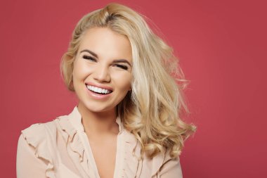Sarışın kıvırcık bob saç modeli ve eğleniyor ve renkli pembe duvar arka planı gülüyor gülümsemek güzel kadınla