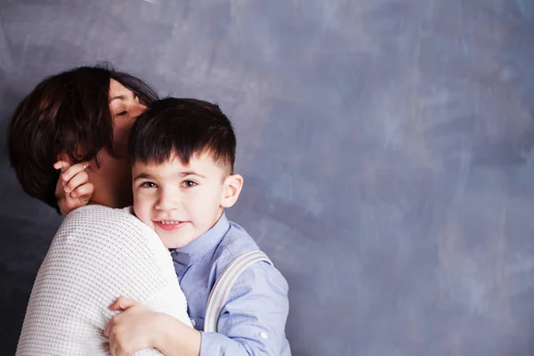 Счастливая мать и сын обнимаются на фоне доски — стоковое фото