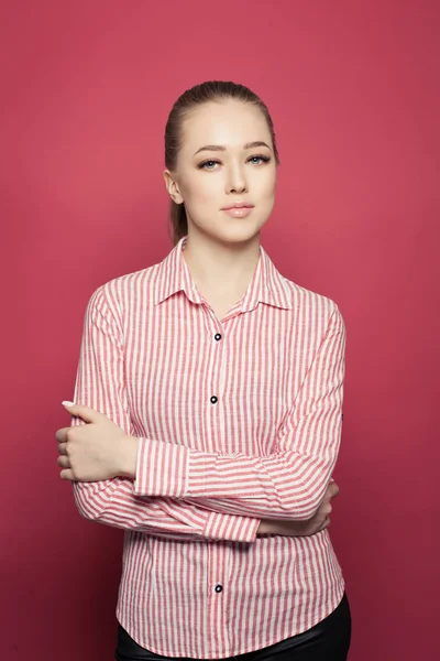 Young successful woman standing against pink wall background.