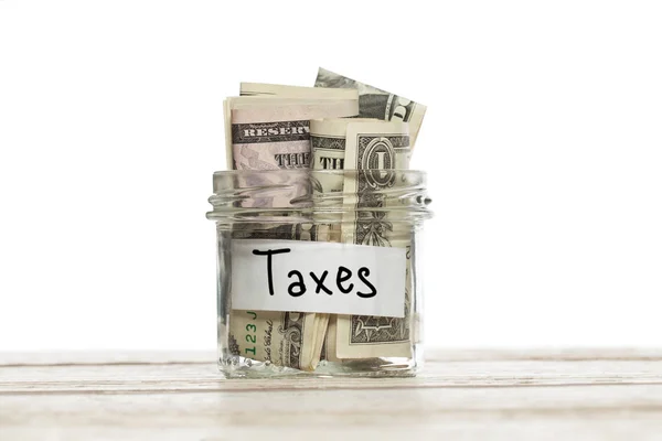Frasco de vidro de poupança com dinheiro para impostos sobre mesa de madeira contra fundo branco — Fotografia de Stock