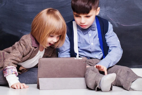 Felices hermanos usando la tableta de PC y jugando juntos. Niños en casa —  Fotos de Stock