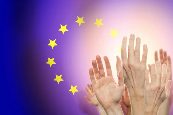 Pessoas levantando as mãos e bandeira União Europa em segundo plano . — Fotografia de Stock
